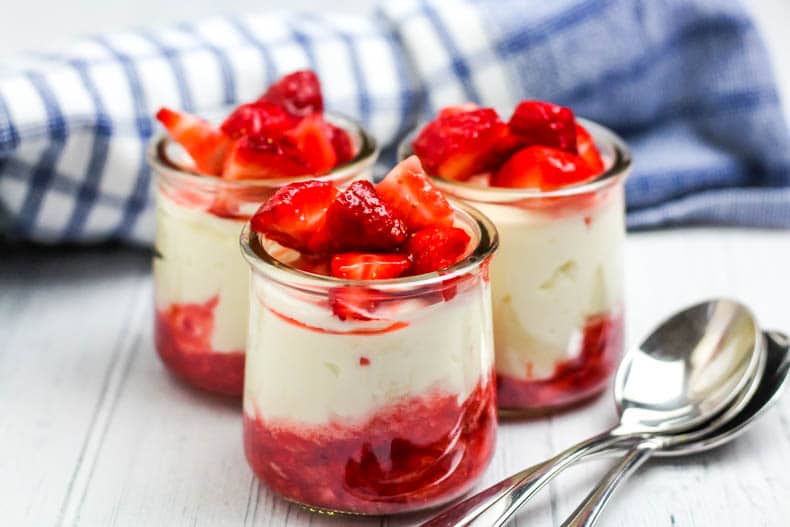 glass jars with white cheesecake and red strawberries